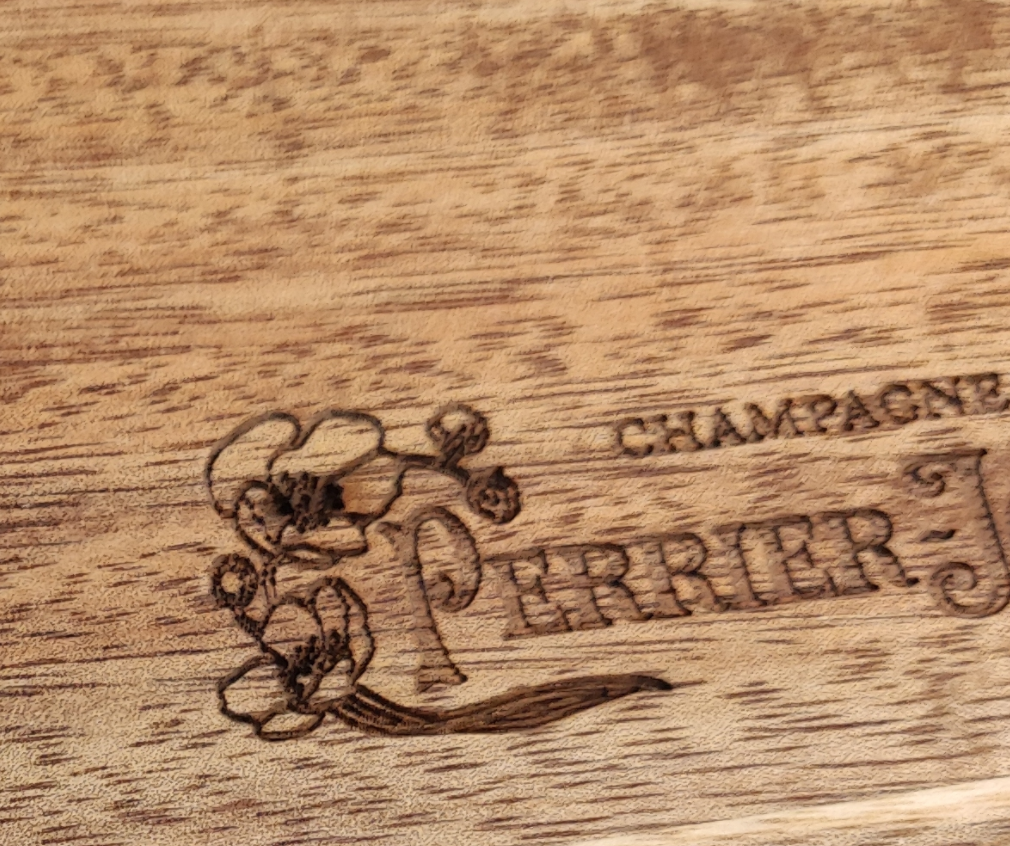 Close-up of laser engraved logo on acacia wood coaster at Chic Homeware factory